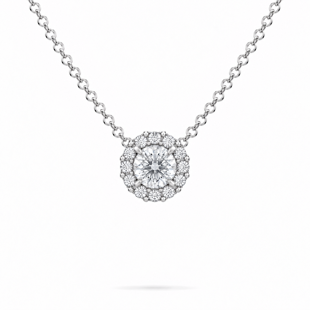 A round brilliant cut moissanite weighing 1ct is framed by a halo of round brilliant cut moissanite, white gold plated sterling silver