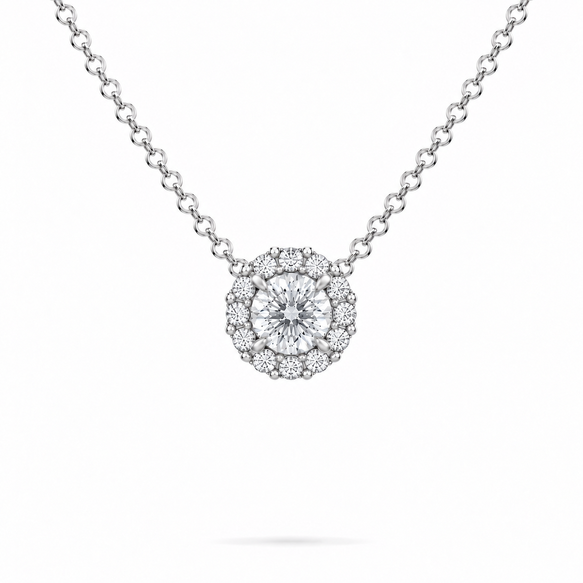 A round brilliant cut moissanite weighing 1ct is framed by a halo of round brilliant cut moissanite, white gold plated sterling silver